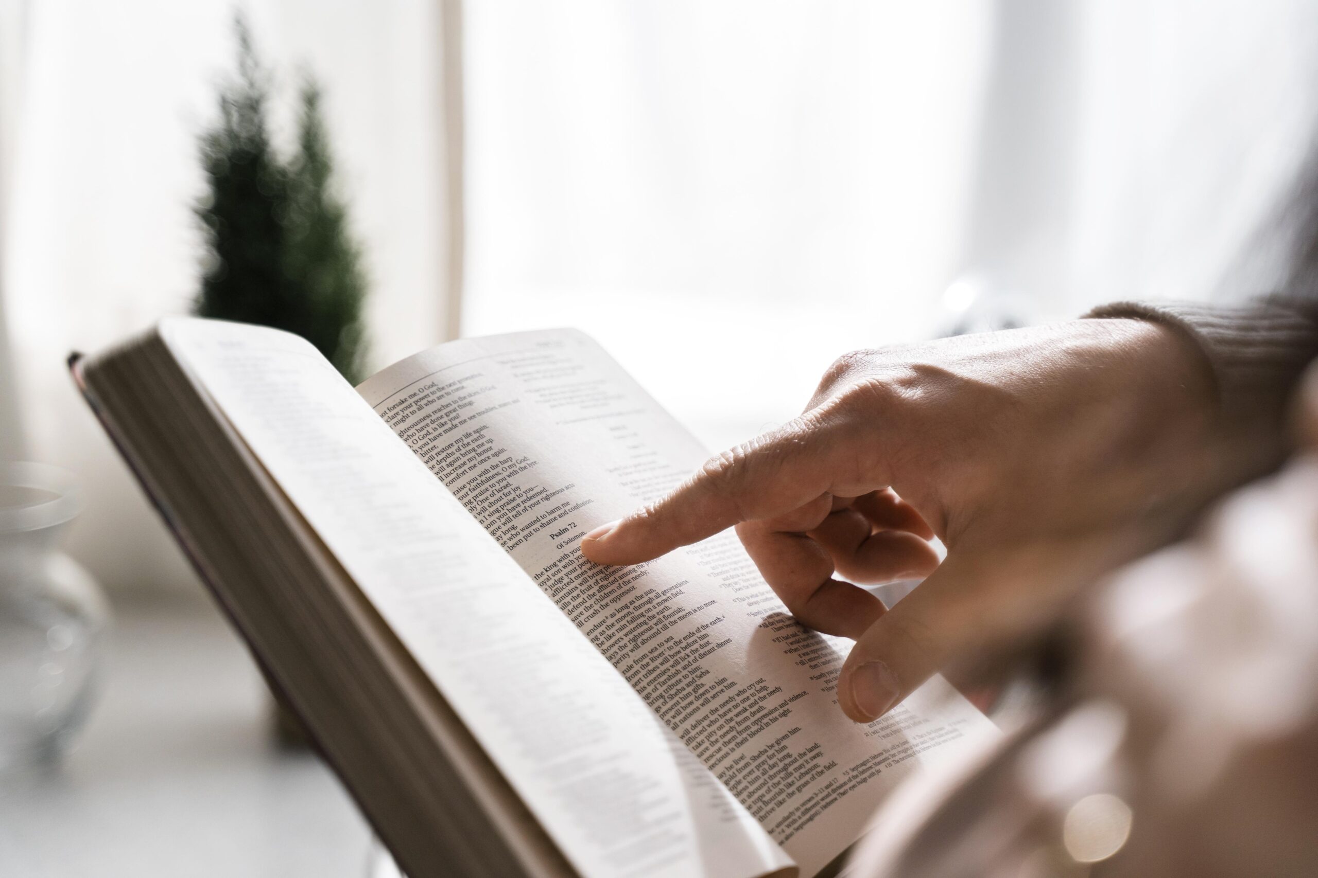 side view of man reading bible with finger
